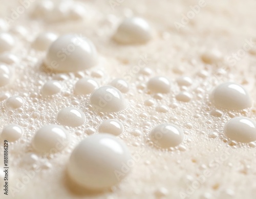 Close up of creamy liquid surface with many small and large white bubbles forming a textured background with soft lighting