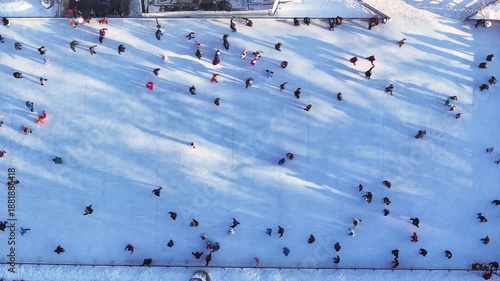 Ice skating occurs outdoors with many enjoying the winter fun