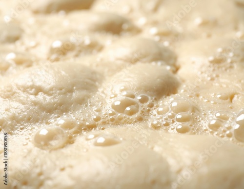 Close up of active baking yeast bubbling and fermenting in warm liquid with soft natural light creating a textured background for food preparation and cooking concepts