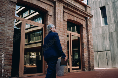 Wallpaper Mural Rear view of senior professional woman walking with digital tablet, showcasing progress, mobility, and confidence in managing tasks with technology on the go. Torontodigital.ca