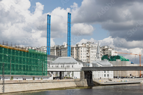 GES-2 power plant building with blue ventilation pipes, Moscow riverbank, construction site, urban architecture, bridge in foreground