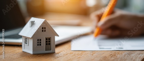 The house model on a desk next to signed real estate contract and pen