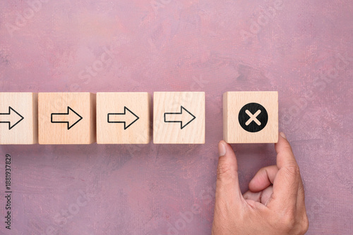 Wooden blocks with arrows ending in a wrong symbol, representing mistake, failure, and negative outcome