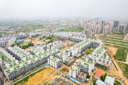 aerial drone shot over symmetric builder floor houses with skyscrapers in the distance showing real estate development near Dwarka expressway India