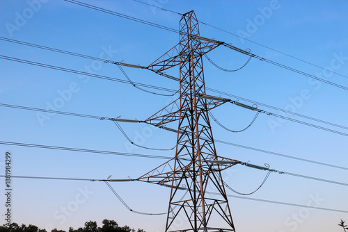 Obraz na plátně Large steel lattice transmission tower set against a clear blue sky, supporting multiple high-voltage power lines via long glass insulators