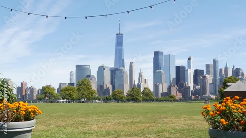 Wallpaper Mural New York City Manhattan Downtown Financial District skyline, World Trade Center tower from New Jersey Liberty state park, United States. Green grass lawn, flowers and skyscraper buildings cityscape. Torontodigital.ca