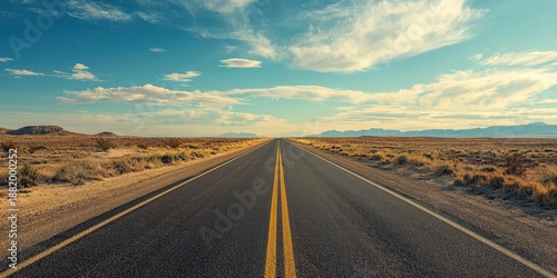 An endless straight road stretching into the distance, with a clear blue sky and scattered clouds above, and a barren landscape with sparse vegetation on either side.