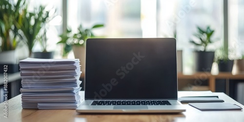 Wallpaper Mural A laptop with a blank screen and a stack of papers on a desk in an office setting. Torontodigital.ca