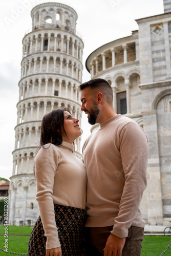 Young woman and man embracing and looking closely at each other at the Tower of Pisa in Italy