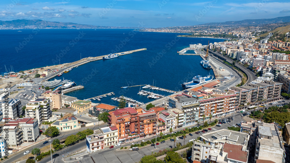 Fototapeta premium Aerial view of the port of Reggio Calabria, in southern Italy. It is a small marina overlooking the Strait of Messina. Sicily can be seen in silhouette on the horizon. It is a sunny summer morning.