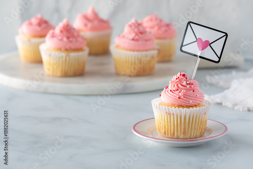 Homemade vanilla cupcakes with pink frosting and sprinkles for Valentine's Day.