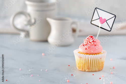 A homemade vanilla cupcake with rose frosting and sprinkles for Valentine's Day.