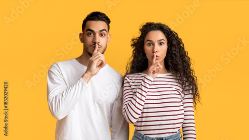 Canvas Print Young arab man and woman showing shh gesture at camera, mysterious middle easter