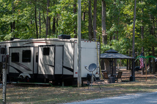 RV travel trailer parked in wooded campground site