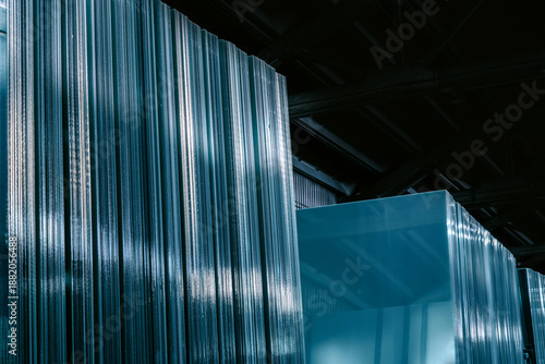 Closeup of clear glass sheets stacked with reflective green edges, suitable for industrial or architectural concepts