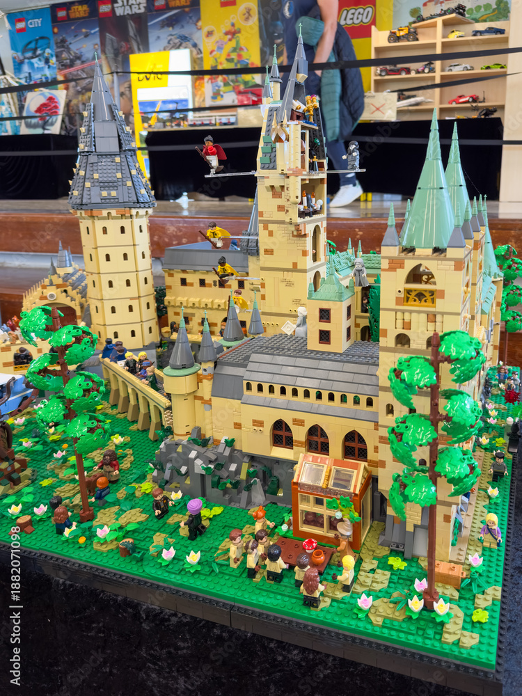 Fototapeta premium LEGO display of Hogwarts Castle from the Harry Potter universe, featuring towers, a greenhouse, and numerous wizard minifigures on a large green baseplate: 06.10.2024-Ljubljana, Slovenia