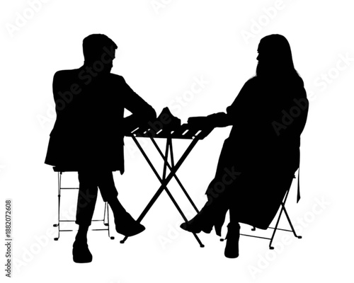 Two silhouetted figures seated at a table, engaged in a quiet moment or conversation