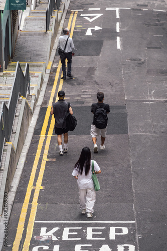 Wallpaper Mural Taken from a high angle, pedestrians walking away along a paved street marked with double yellow lines and directional arrows. "KEEP CLEAR" sign painted on the asphalt. Hong Kong, China. Torontodigital.ca