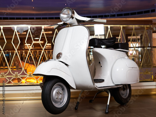Vintage white scooter with black seat in an elegant indoor setting in low angle shot