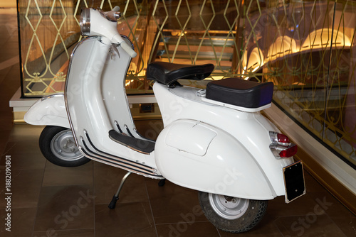 White scooter parked indoors next to an ornate golden railing