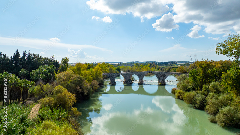 Fototapeta premium Belkis Koprusu areial dron photo. Seljuk bridge in Aspendos. The Eurymedon Bridge. Aspendos Yolu Belkis Mevkii. Turkey. Crooked Bridge over the Kopruchay (Euremedon) River near Aspendos, in Pamphylia,