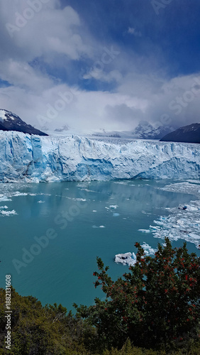 Wallpaper Mural Massive ice wall of Perito Moreno Glacier meeting turquoise water, framed by Patagonian mountains and firetrees in Los Glaciares National Park, Argentina. Torontodigital.ca