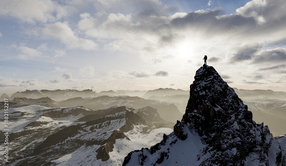 Naklejka premium Climber Standing On Snowy Mountain Peak With Sunrise Over Vast, Misty Range