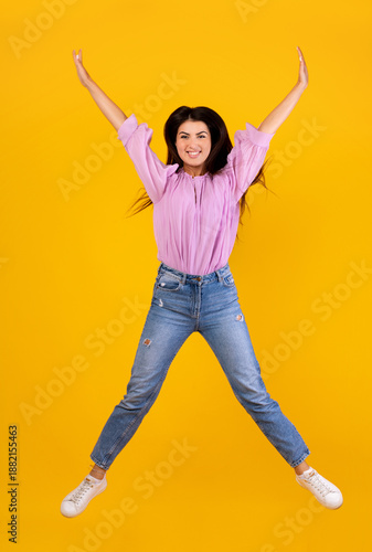 Euphoria concept. Full length portrait on positive armenian woman jumping and fooling isolated on yellow studio background, crop. Excited female celebrating win
