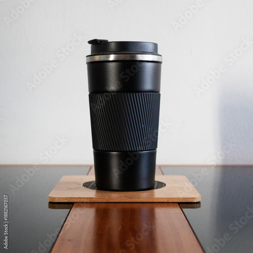 Black thermal cup on a board on the table