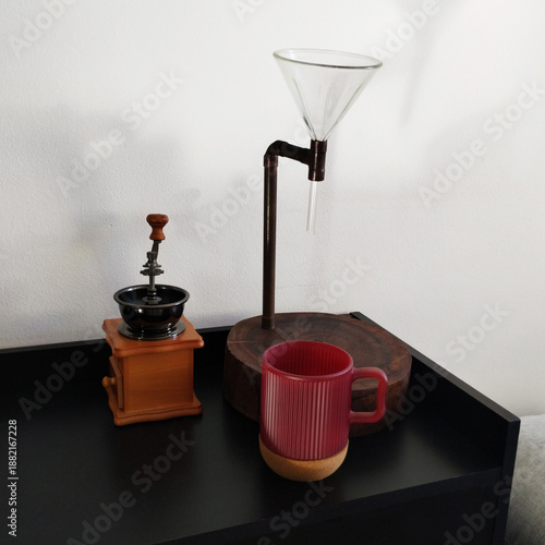 Rustic coffee maker, coffee grinder, and red mug on the black shelf