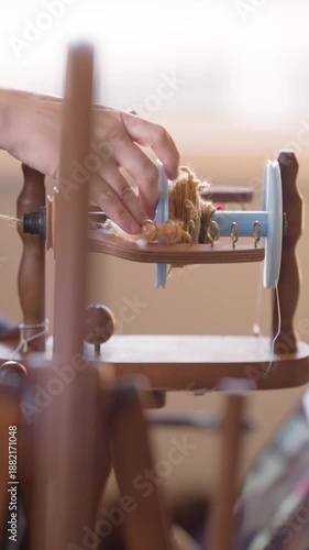 3d printed bobbin on a traditional wooden flyer and spinning wheel.  Vertical view of a 3d printed bobbin being turned by hand, then spun by the spinning wheel as it winds newly made yarn.