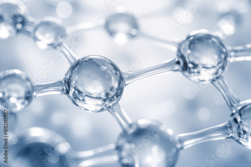 Close-up of transparent glassy spheres connected by smooth cylindrical rods representing a molecular structure on a blue background with soft lighting and reflections.