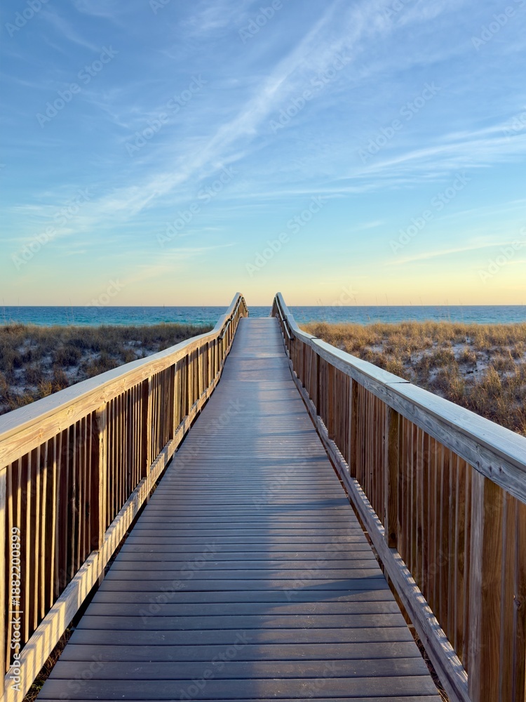Fototapeta premium A wooden boardwalk to the Florida beach at sunset over the sand dunes.