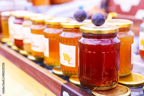 Fair, honey supermarket. Beekeepers, various types of honey in glass jars and other various dishes, including honeycombs and honey with nuts and cute doll bees, are on the shelves for sale. Healthy