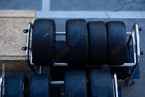 Mechanic performs automotive maintenance on red race car wheel and tire. focused pit stop service requiring precision for high speed vehicle performance and competition