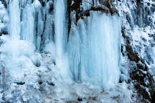 Photography Icefall formation at Rudawka Rymanowska, featuring shimmering blue icicles cascading down a river cliff in the winter landscape, showcasing natures beauty and cold climate