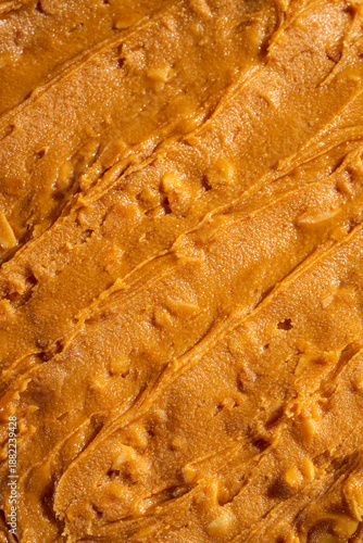Creamy peanut butter texture background with smooth swirls and natural organic appearance. Ideal for food packaging, healthy lifestyle concepts, vegan and plant-based nutrition, cooking, baking