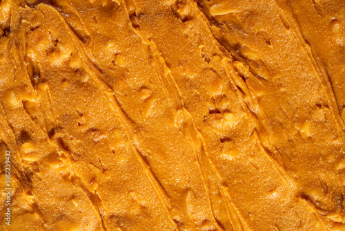 Creamy peanut butter texture background with smooth swirls and natural organic appearance. Ideal for food packaging, healthy lifestyle concepts, vegan and plant-based nutrition, cooking, baking