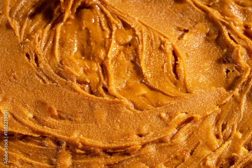Creamy peanut butter texture background with smooth swirls and natural organic appearance. Ideal for food packaging, healthy lifestyle concepts, vegan and plant-based nutrition, cooking, baking