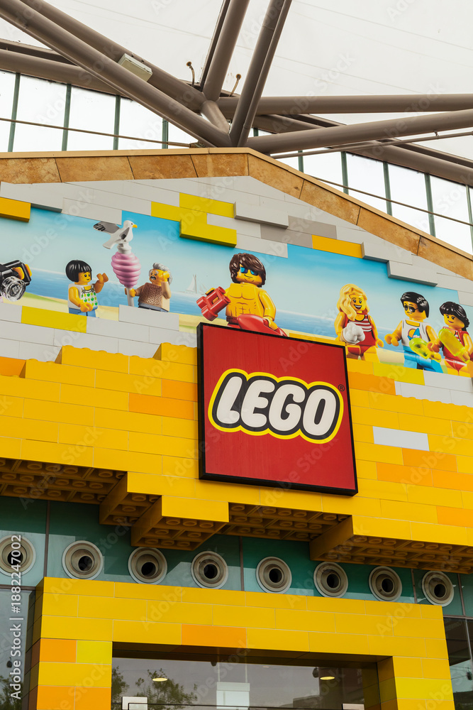 Fototapeta premium Singapore - January 7, 2026: People walk in front of a LEGO store in Singapore. The building features bright colors and playful designs. Families and children enjoy the fun atmosphere