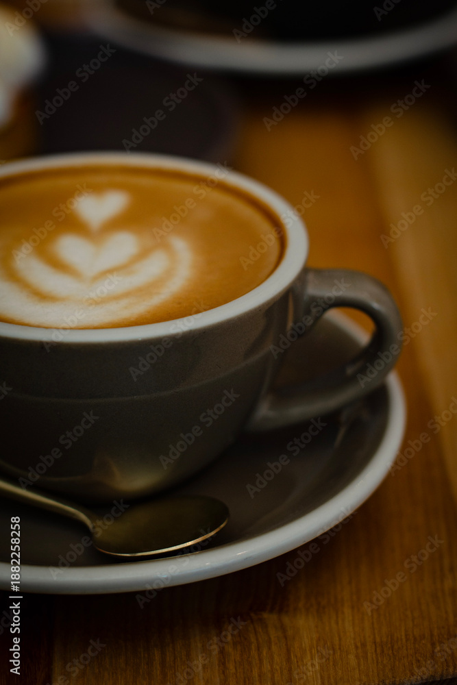 Obraz premium Hot cappuccino on a wooden table in a cozy café atmosphere