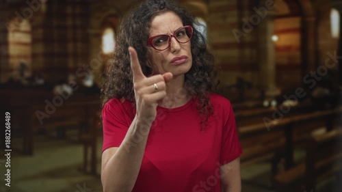 Woman in red shirt finger pointing to camera in church building with stern expression; anger rebuke admonition warning.