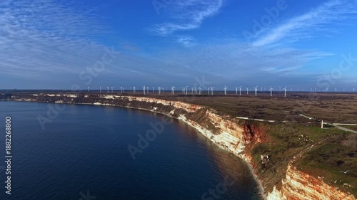 Wallpaper Mural Cliffs rise above the water with wind turbines placed along the coastline. The scene shows a clear sky with a few clouds. Nature and technology blend at this coastal location. Torontodigital.ca