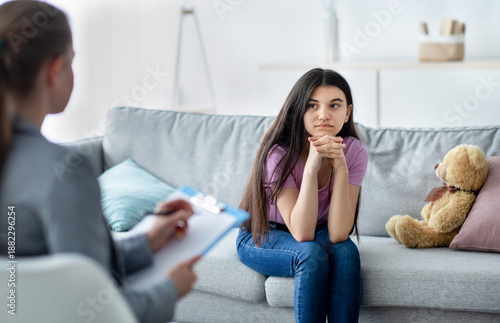 Фотография Female psychologist consulting depressed Indian teenage girl at office