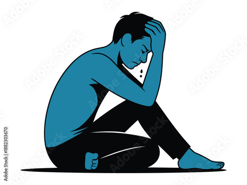 A man sits on the floor with his head in his hand, looking stressed and overwhelmed.