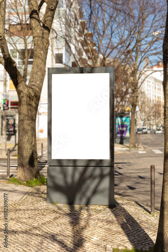Blank outdoor advertising billboard on a city sidewalk in Lisbon, Portugal. Urban street scene with copy space, ideal for marketing, branding, public communication, and advertising mockups.