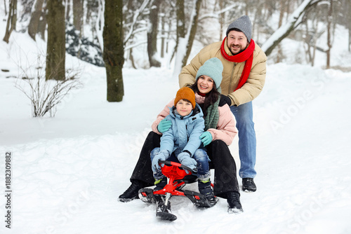 Quadro em tela Happy family having fun with sledge outdoors on winter day, space for text