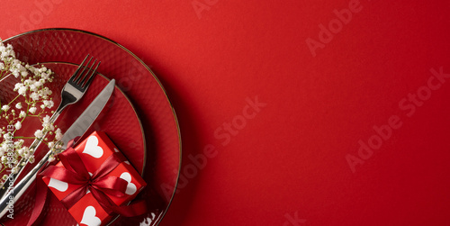 A romantic Valentine banner scene features a red plate with silver cutlery, a wrapped gift with heart motif, and delicate florals for a festive celebration © ActionGP
