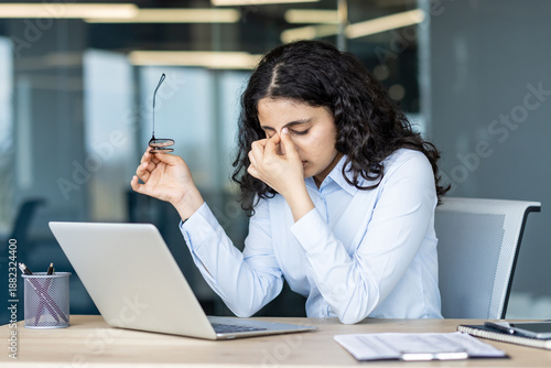Canvas Print Stressed young woman working at office desk and rubbing eyes from headache, feel