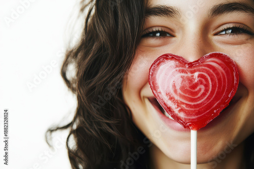 Close up portrait of a happy young woman with a red valentine love heart lollipop